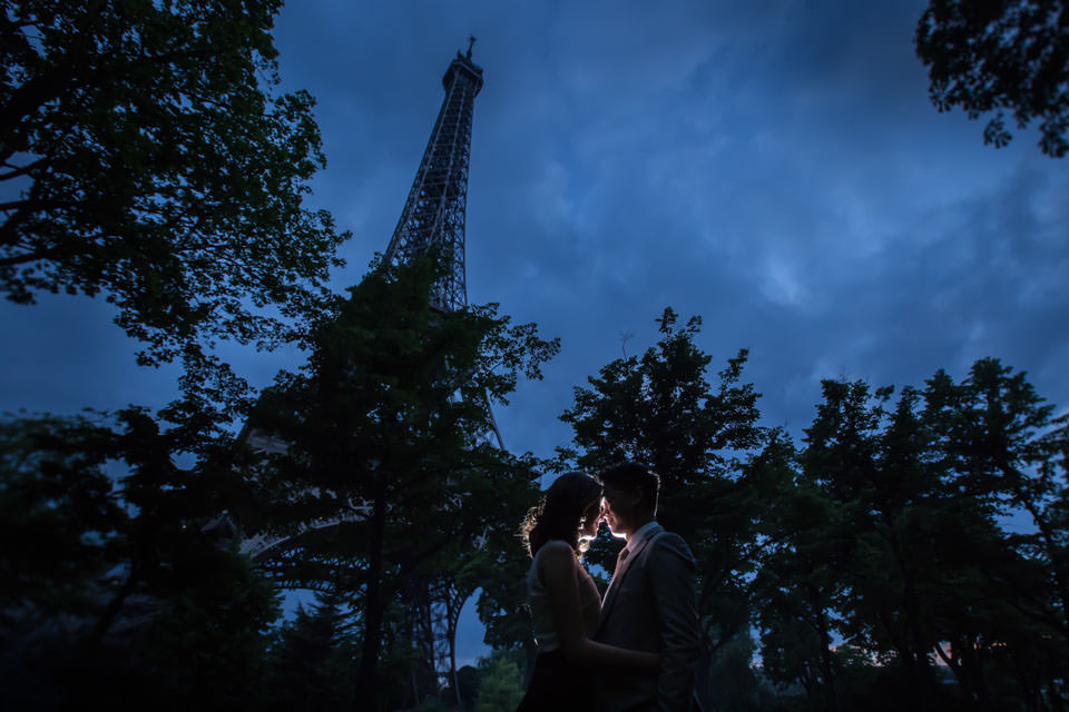 Couple standing face to face at the foot of the Eiffel Tower at night