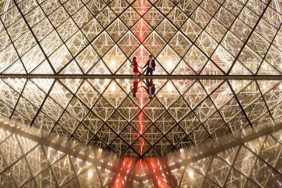 Couple posing by night at le Louvre museum