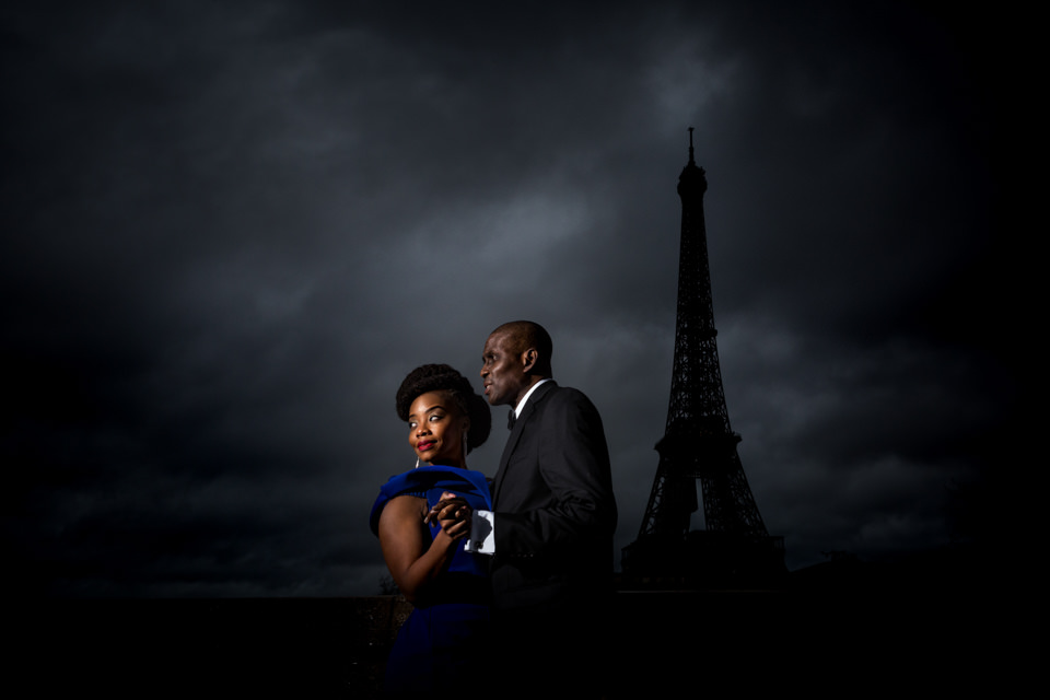 Elegant couple posing at dusk in front of the Eiffel Tower