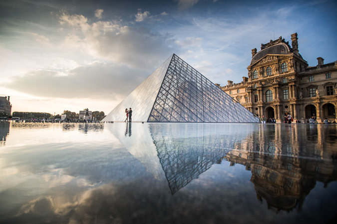 Couple walking in front of the Louvre Pyramid early in the morning