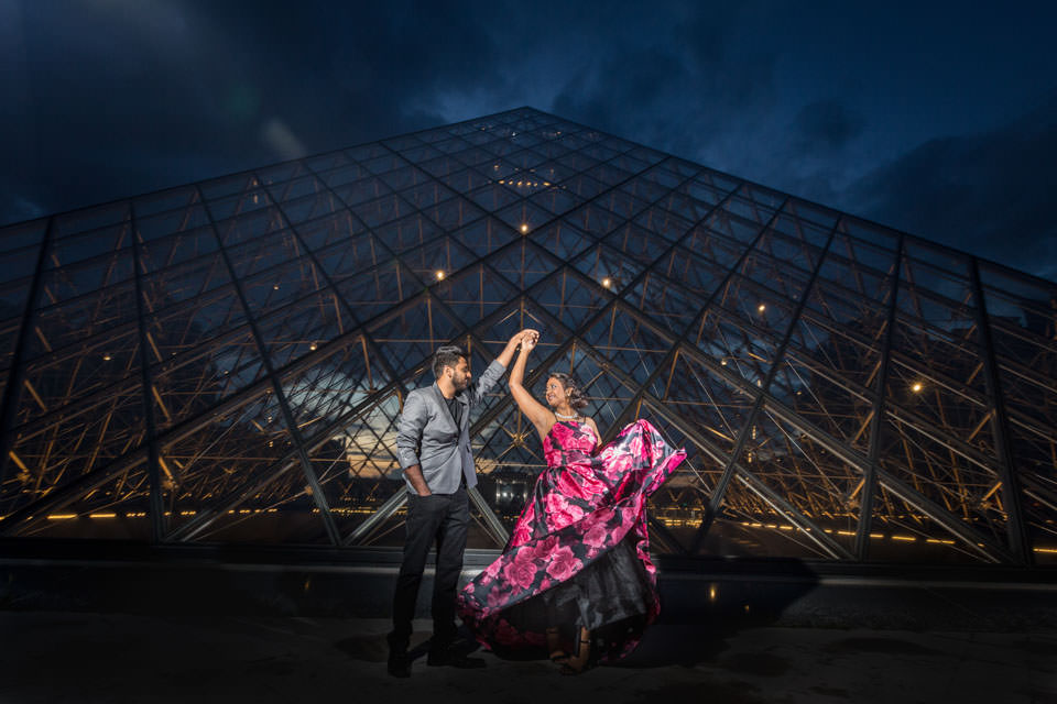 Couple dancing in front of the Louvre Pyramid at night