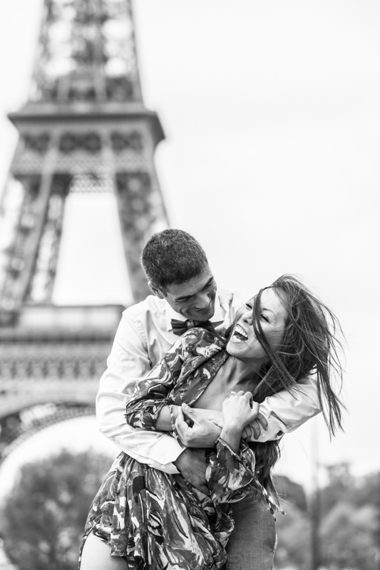 Man hugging his laughing partner with the Eiffel Tower in the background