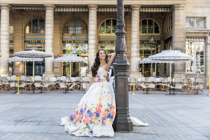 Quinceanera posing in graphic dress in front of a Parisian café